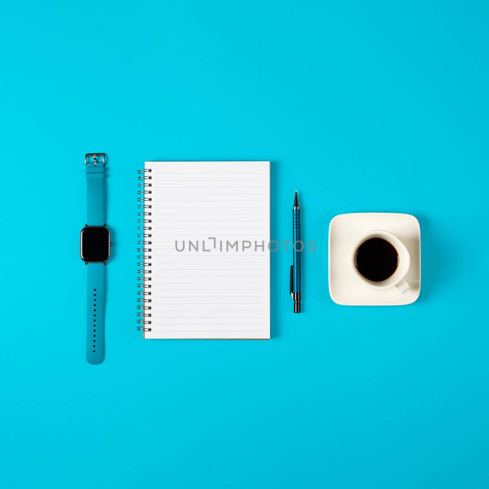 Notepad, watch, pen and a cup of coffee isolated on blue background. Notepad with copy space. Office, business, discreet style.