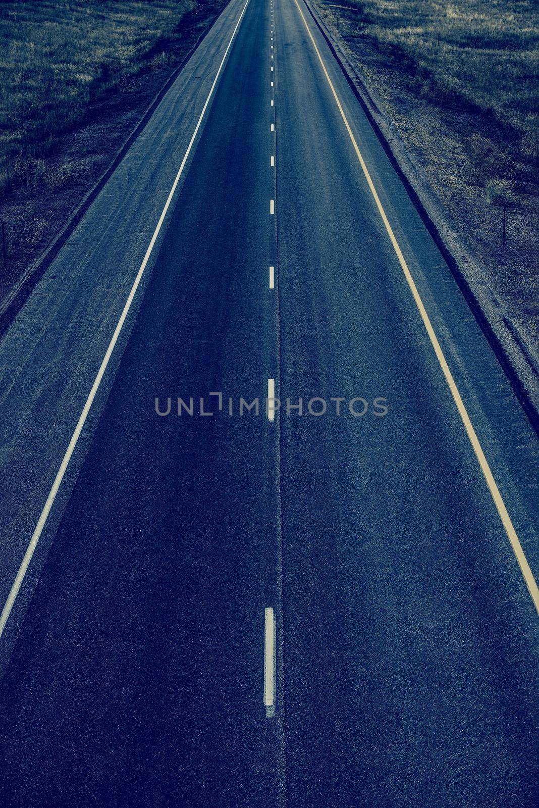 Empty Straight Two Lanes Highway From Above. Fresh Highway Pavement. Dark Blue Color Grading. by welcomia