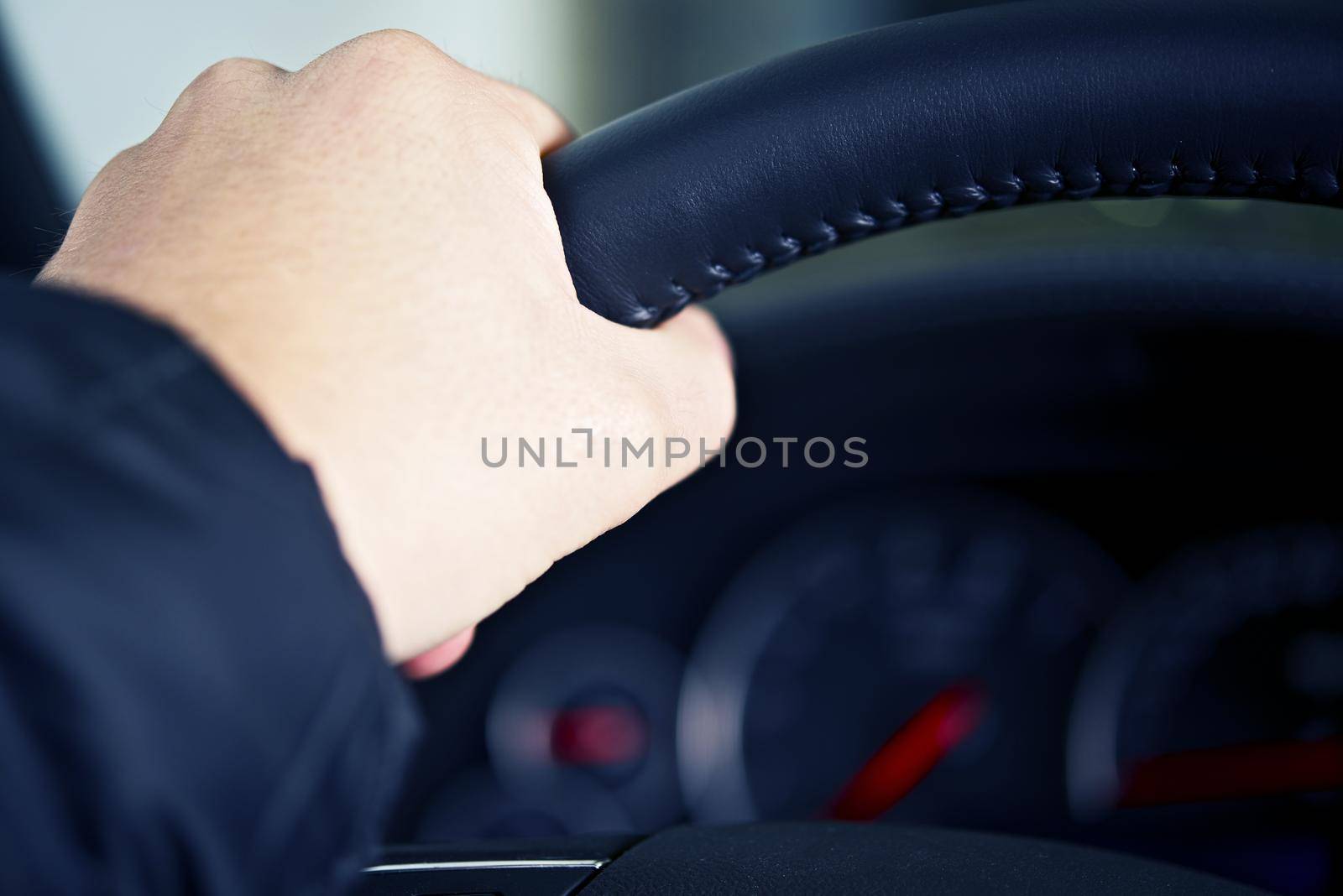 Men Left Hand on Car Steering Wheel. Driving Theme. Transportation Photo Collection.
