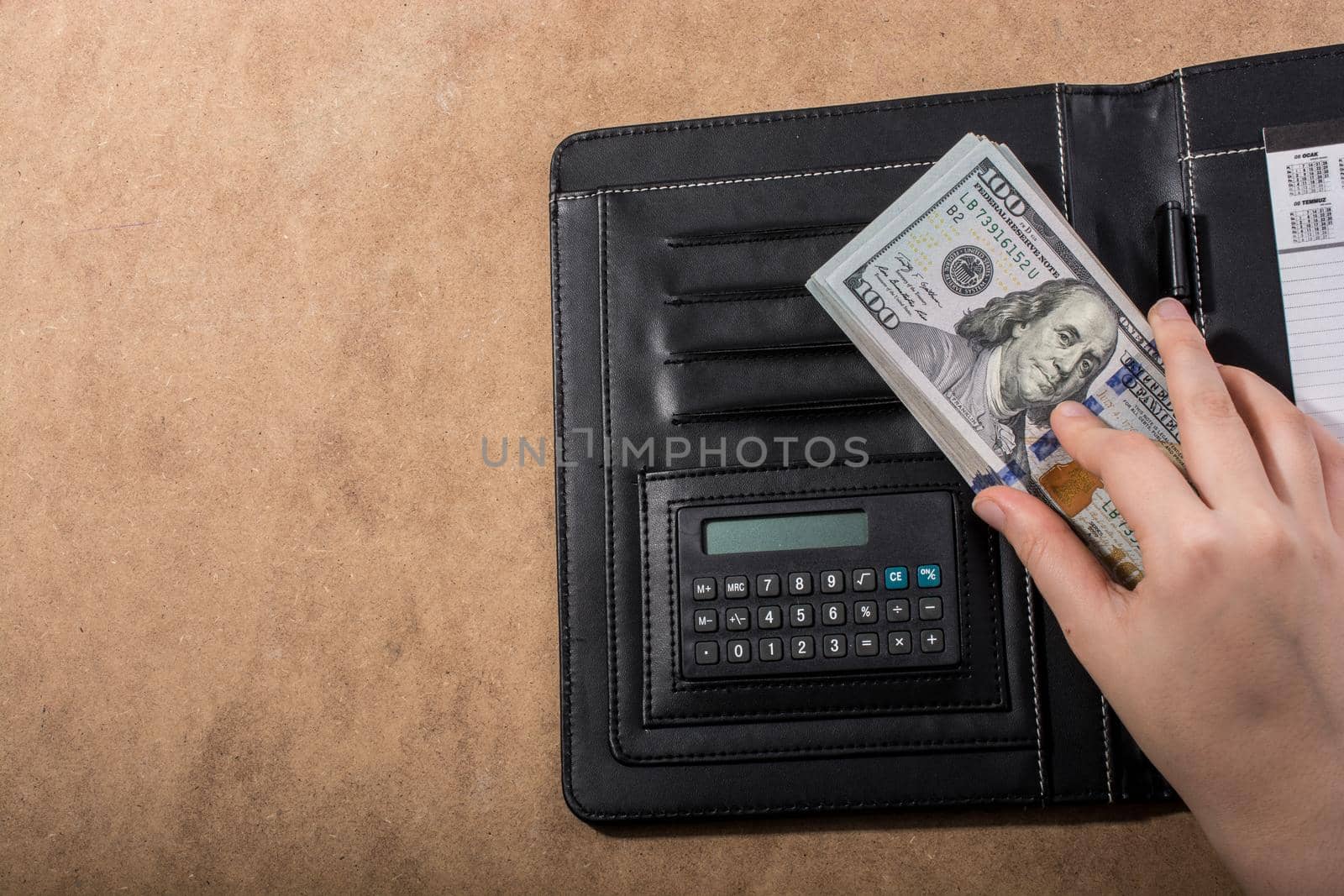 Hand holding American dollar banknotes beside a calculator