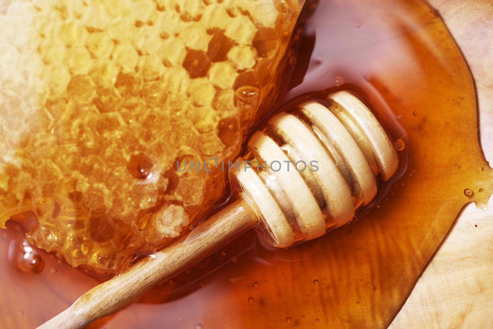 Honeycomb with Wooden Dipper on Wooden Plate Closeup by welcomia