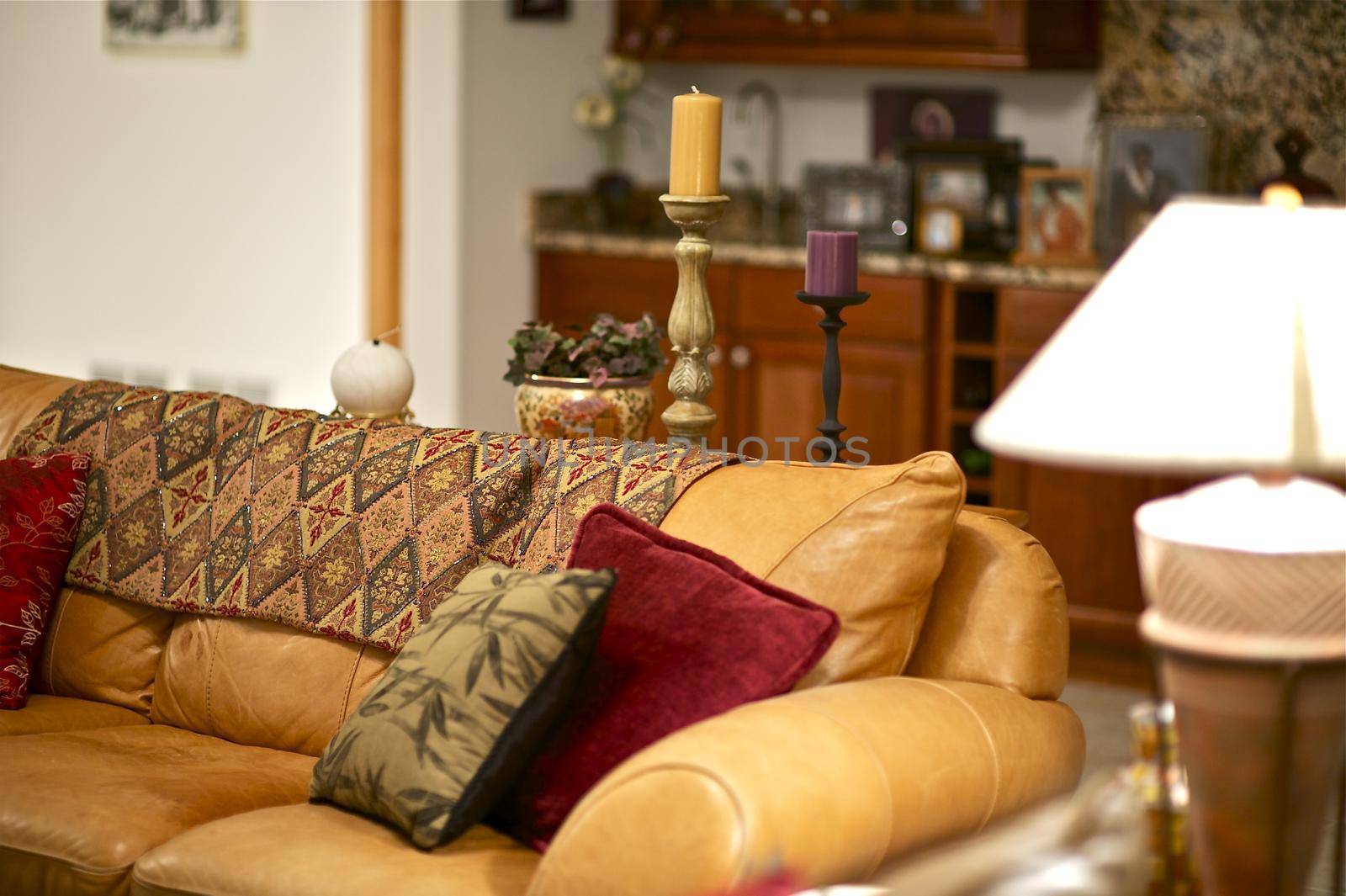 Luxury Home Interior - Living Room. Leather Orange Sofa, Decorative Pillows and Candles.