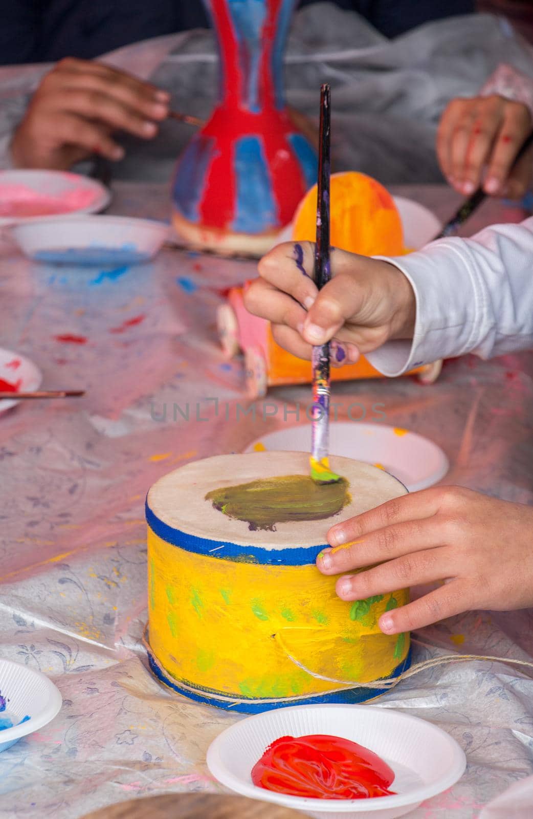 Young children decorating handmade drum