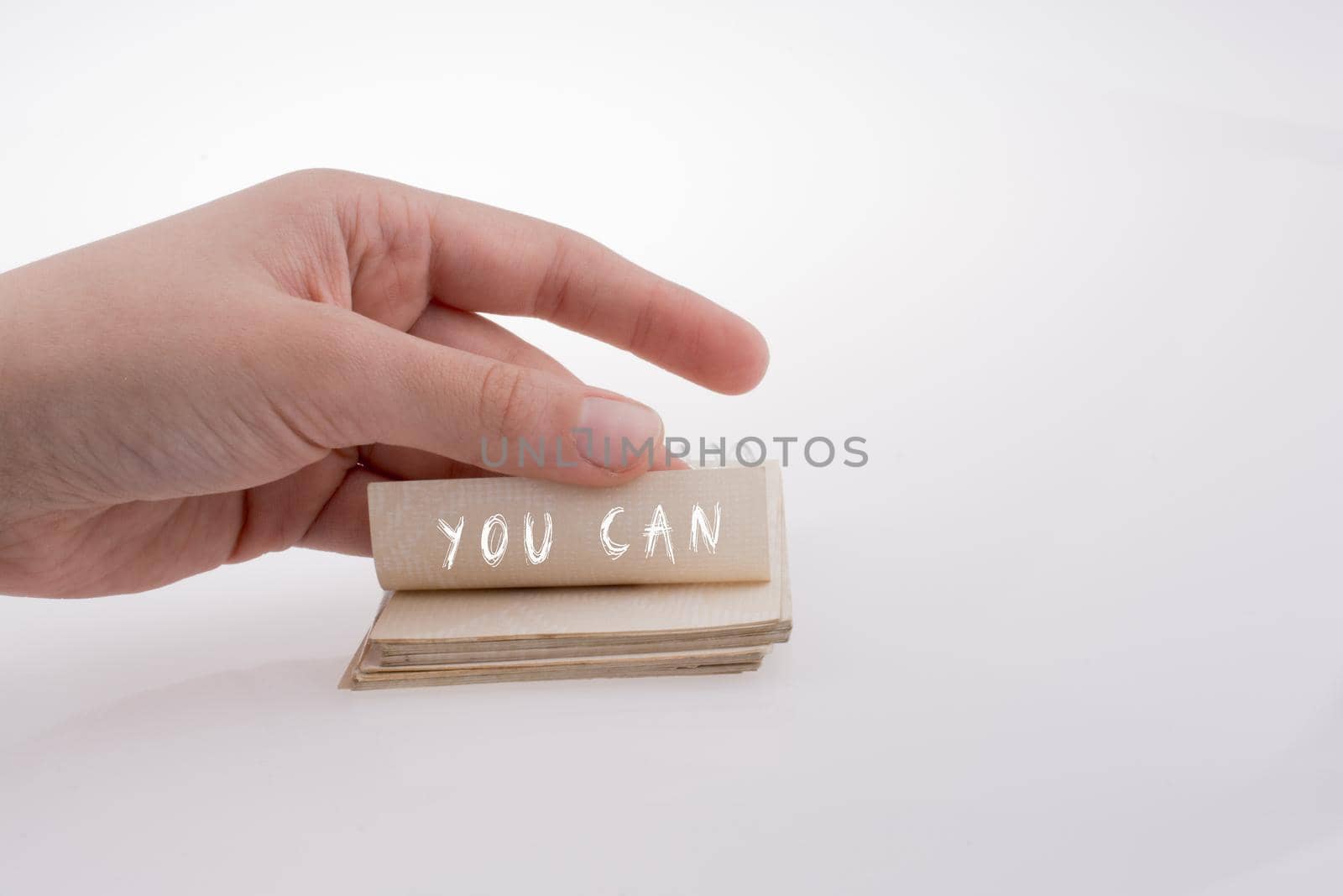 Hand holding paper with note YOU CAN on a white background