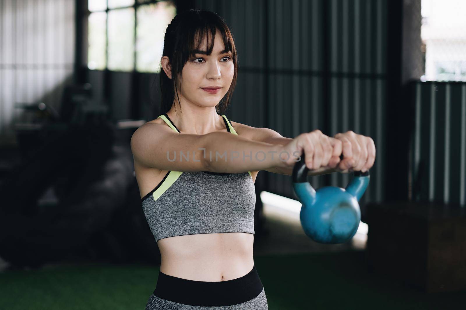 Woman in exercise gear workout with dumbbells during an exercise class at the gym. lifestyle and healthy, fitness, gym exercise, workout concept. by itchaznong
