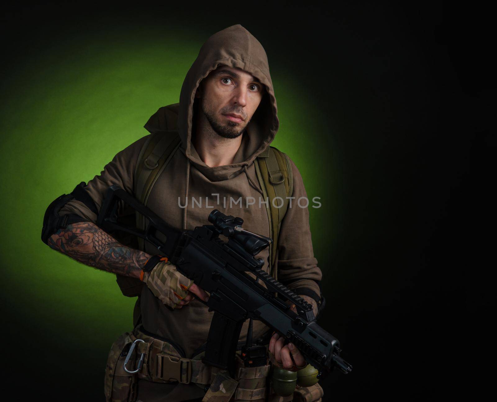 man Stalker with a gun with an optical sight and a backpack on a dark background with emotions looking, aiming, watching, sneaking