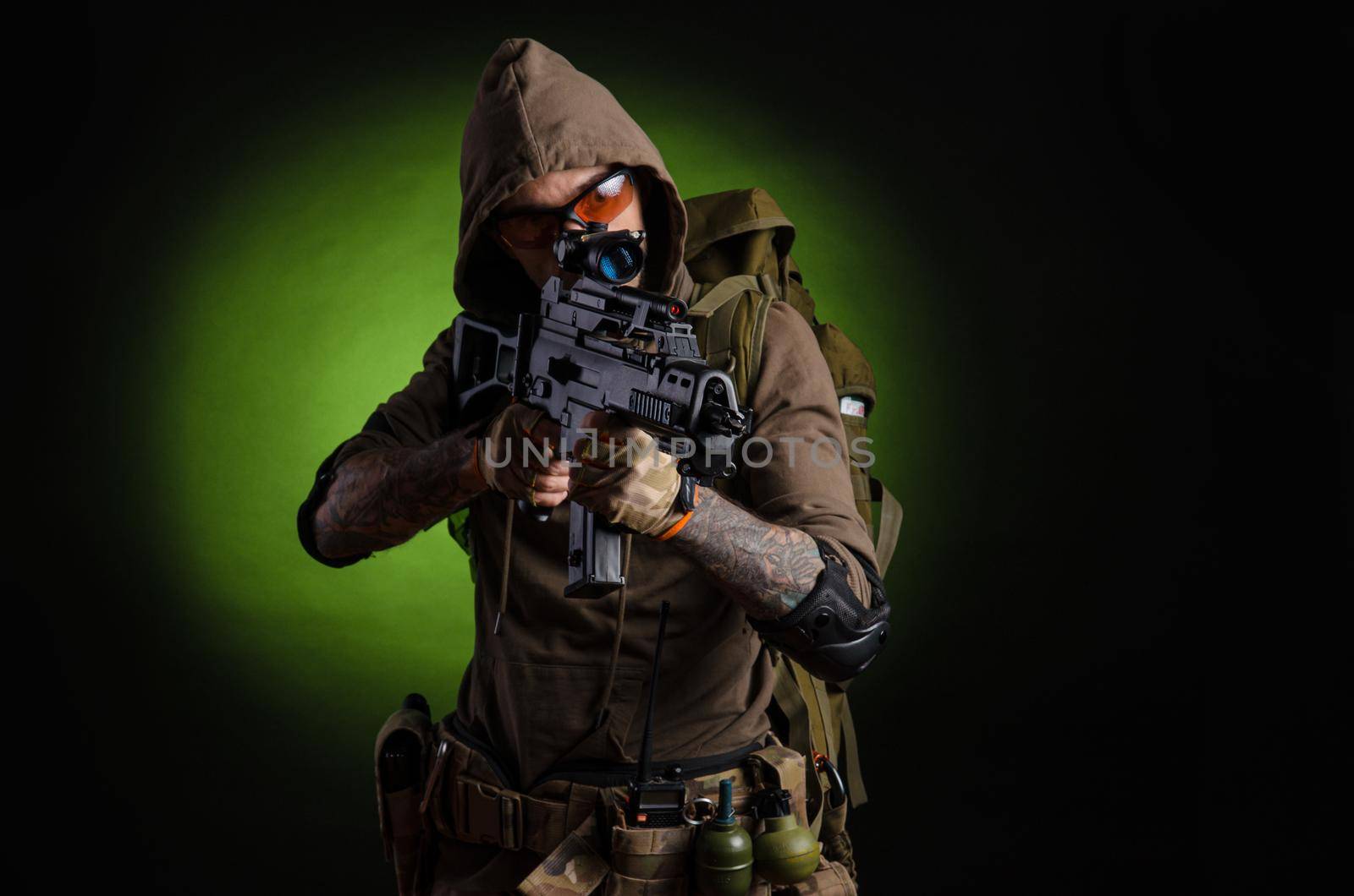 man Stalker with a gun with a telescopic sight and a backpack in a gas mask on a dark background with emotions looking, aiming, watching, sneaking by Rotozey