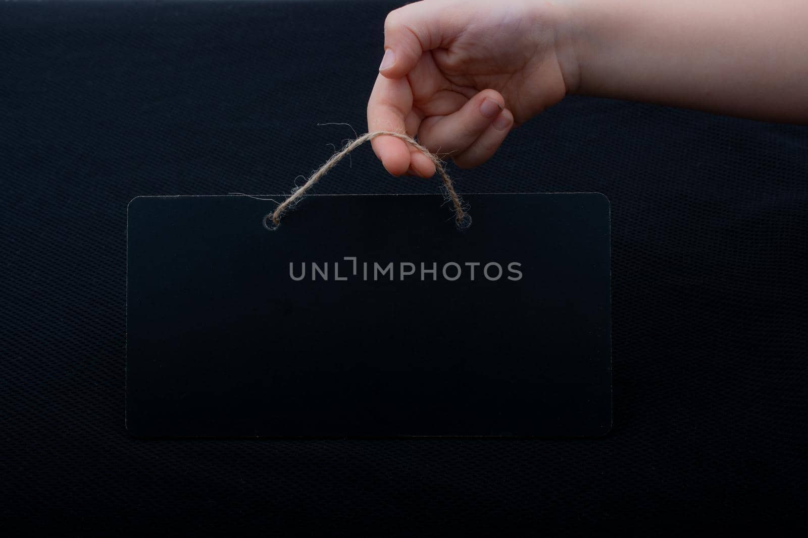 Rectangular shaped black notice board in hand on black background