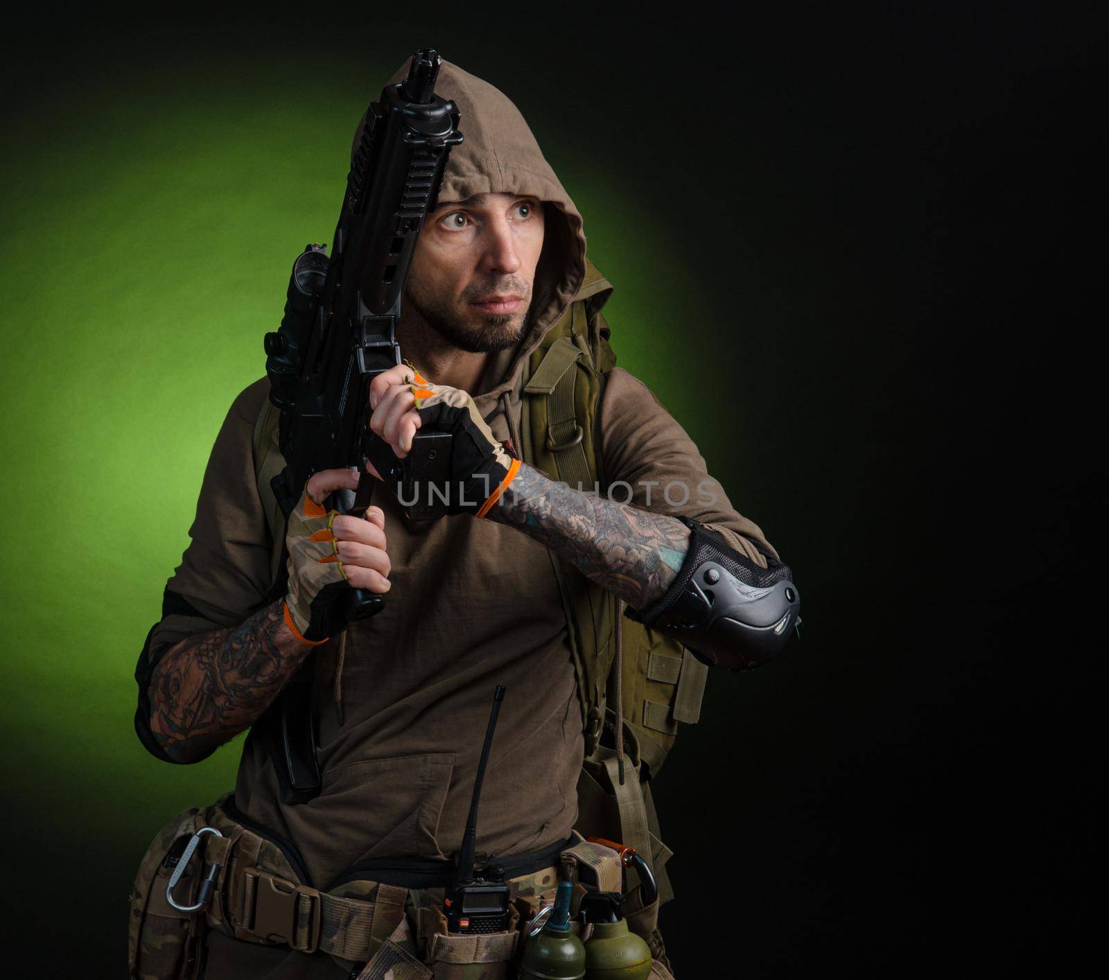 the man Stalker with a gun with an optical sight and a backpack on a dark background with emotions looking, aiming, watching, sneaking