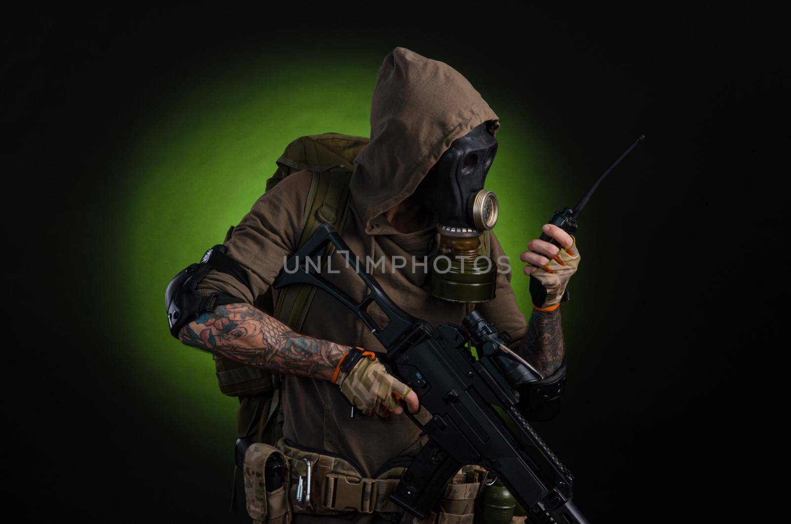 man Stalker with a gun with a telescopic sight and a backpack in a gas mask on a dark background with emotions looking, aiming, watching, sneaking