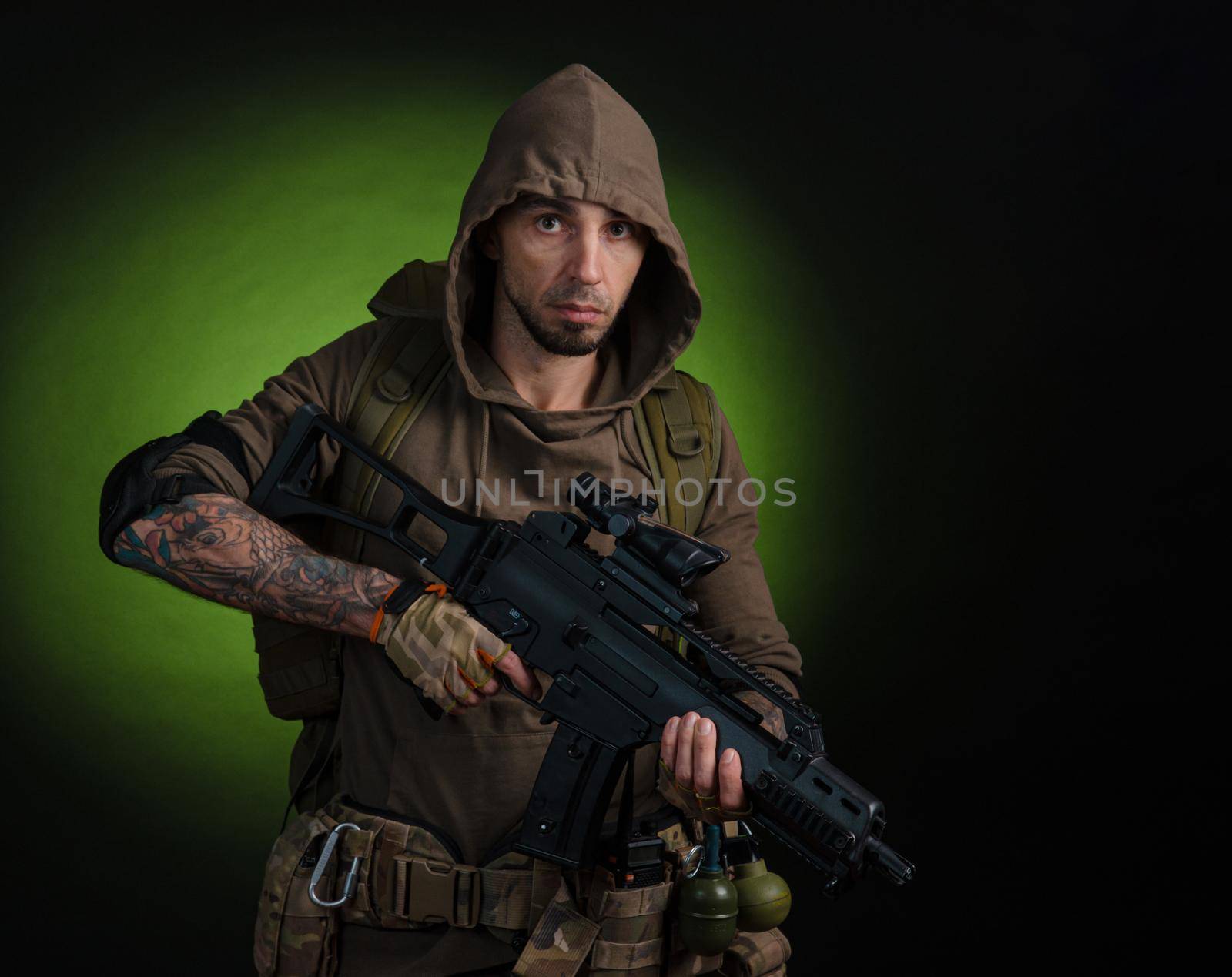 man Stalker with a gun with an optical sight and a backpack on a dark background with emotions looking, aiming, watching, sneaking