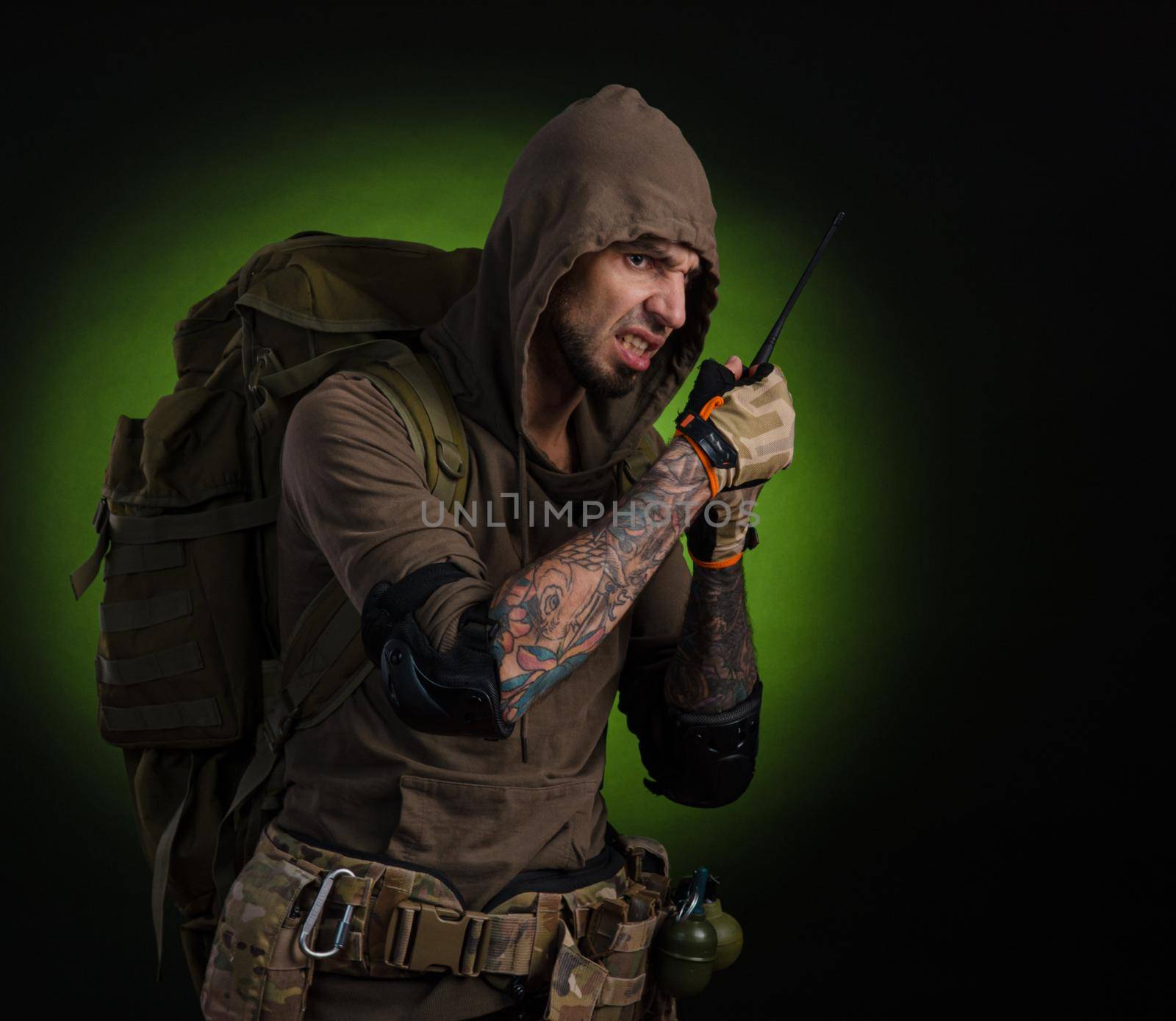 man Stalker with a gun with an optical sight and a backpack on a dark background with emotions looking, aiming, watching, sneaking