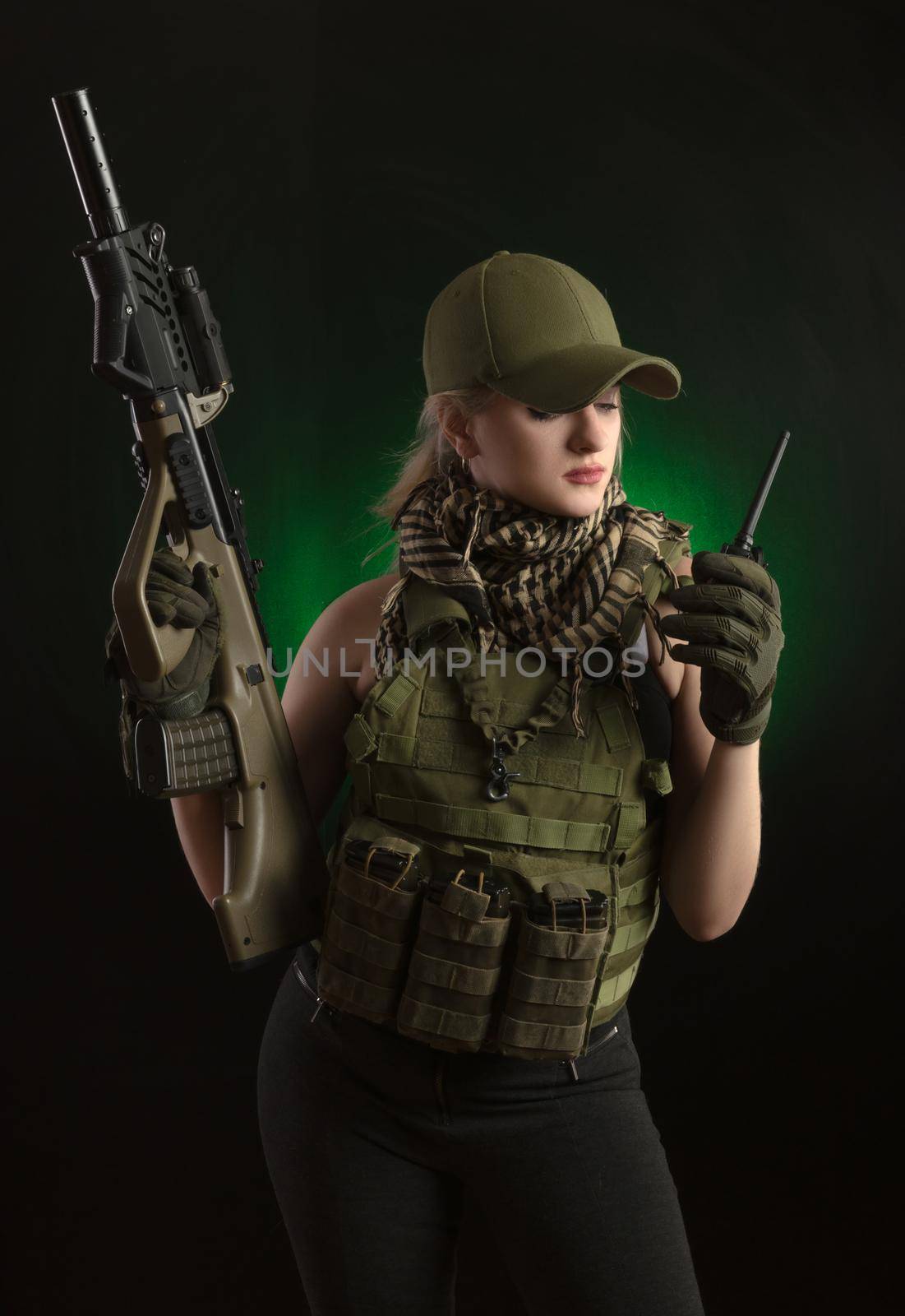 girl in military special clothes posing with a gun in his hands on a dark background in the haze