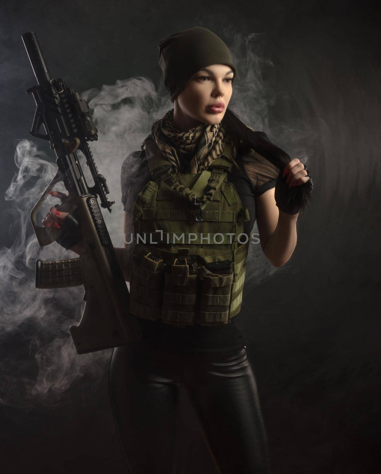 the girl in military special clothes posing with a gun in his hands on a dark background in the haze by Rotozey