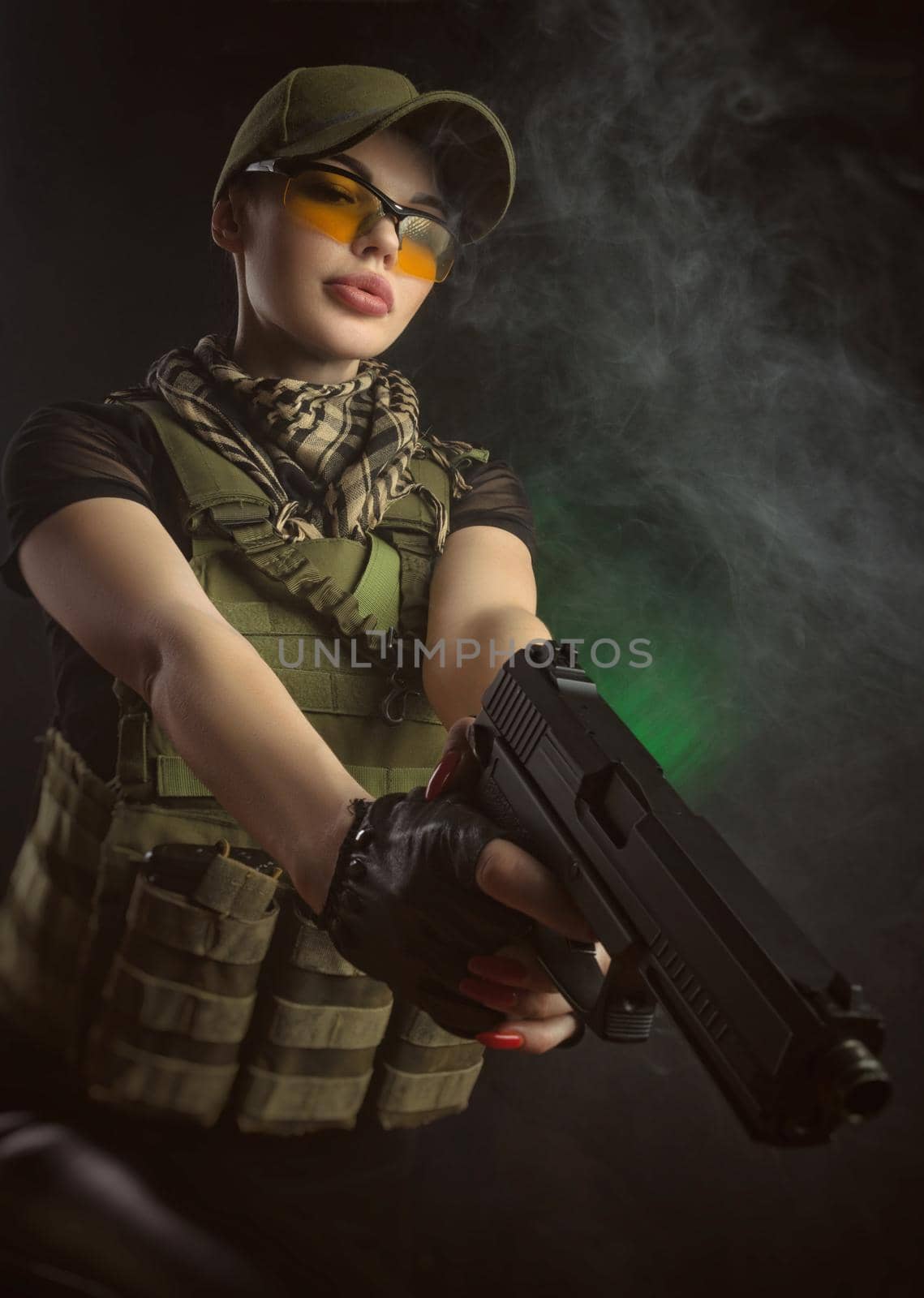 the girl in military special clothes posing with a gun in his hands on a dark background in the haze by Rotozey