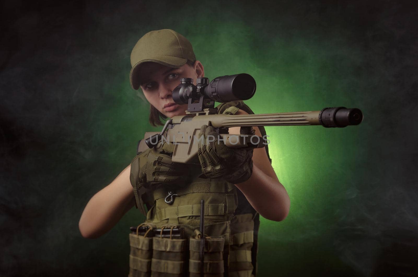 girl in military special clothes posing with a gun in his hands on a dark background in the haze