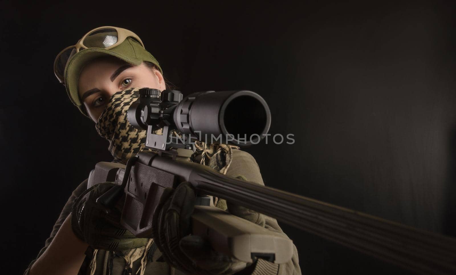 girl in military special clothes posing with a gun in his hands on a dark background in the haze