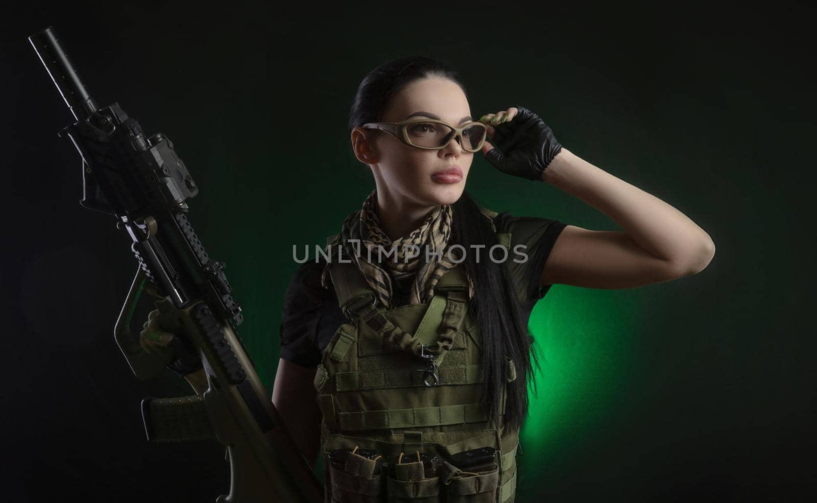 girl in military special clothes posing with a gun in his hands on a dark background in the haze