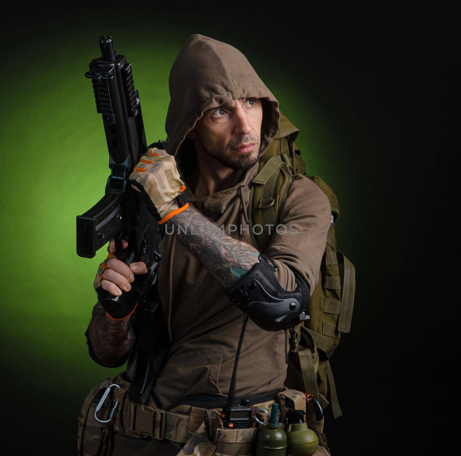 man Stalker with a gun with an optical sight and a backpack on a dark background by Rotozey