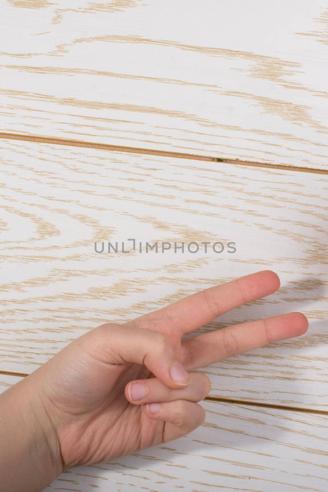 Hands making rock, paper, scissors gesture on a wooden background