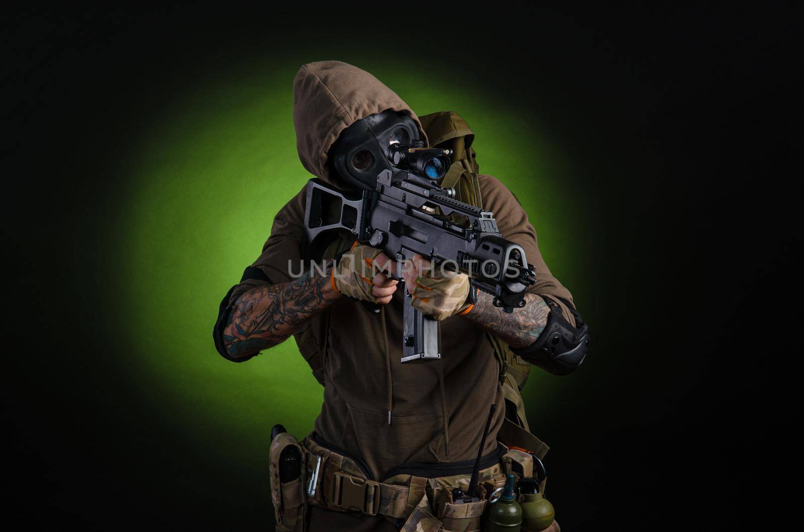 man Stalker with a gun with a telescopic sight and a backpack in a gas mask on a dark background with emotions looking, aiming, watching, sneaking