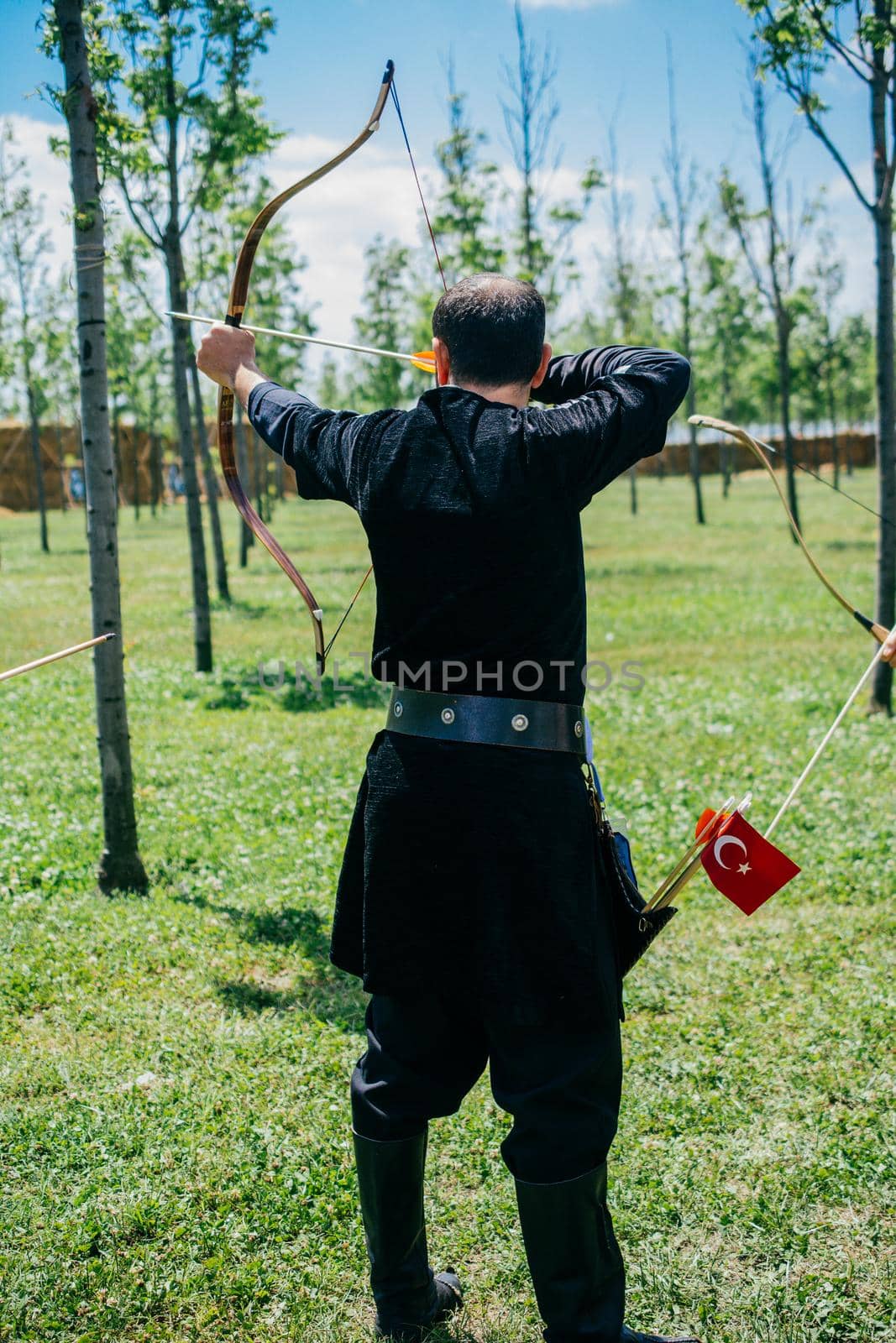 Archer with bow  in traditional clothes shooting an arrow