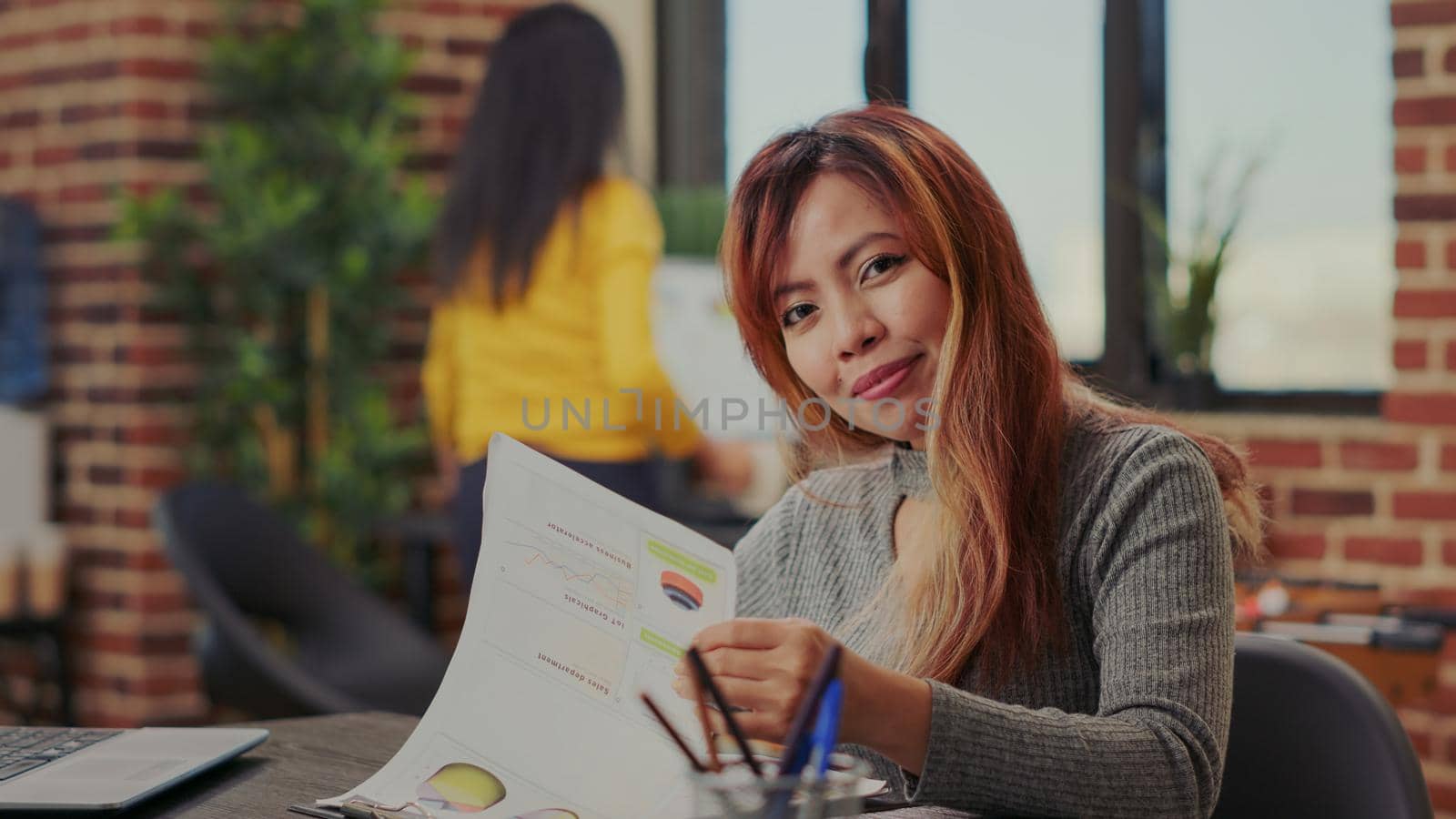 Portrait of office worker looking at financial papers to plan marketing presentation for development. Business woman using graphs analysis to work on successful investment and growth.