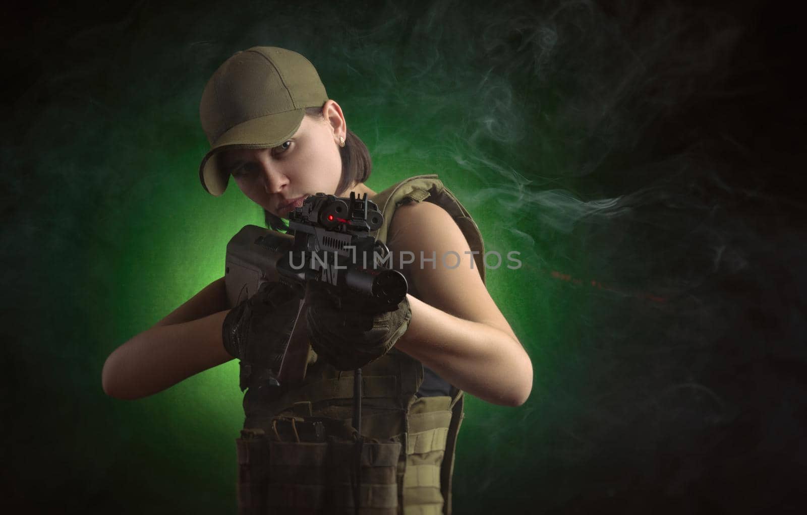 girl in military special clothes posing with a gun in his hands on a dark background in the haze