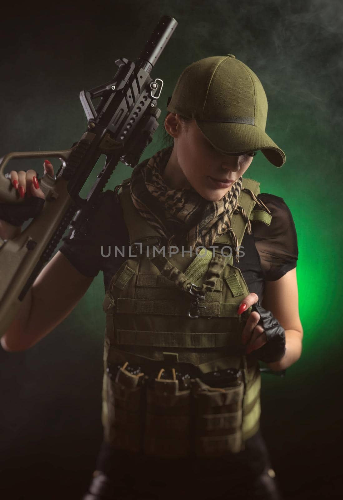 girl in military special clothes posing with a gun in his hands on a dark background in the haze