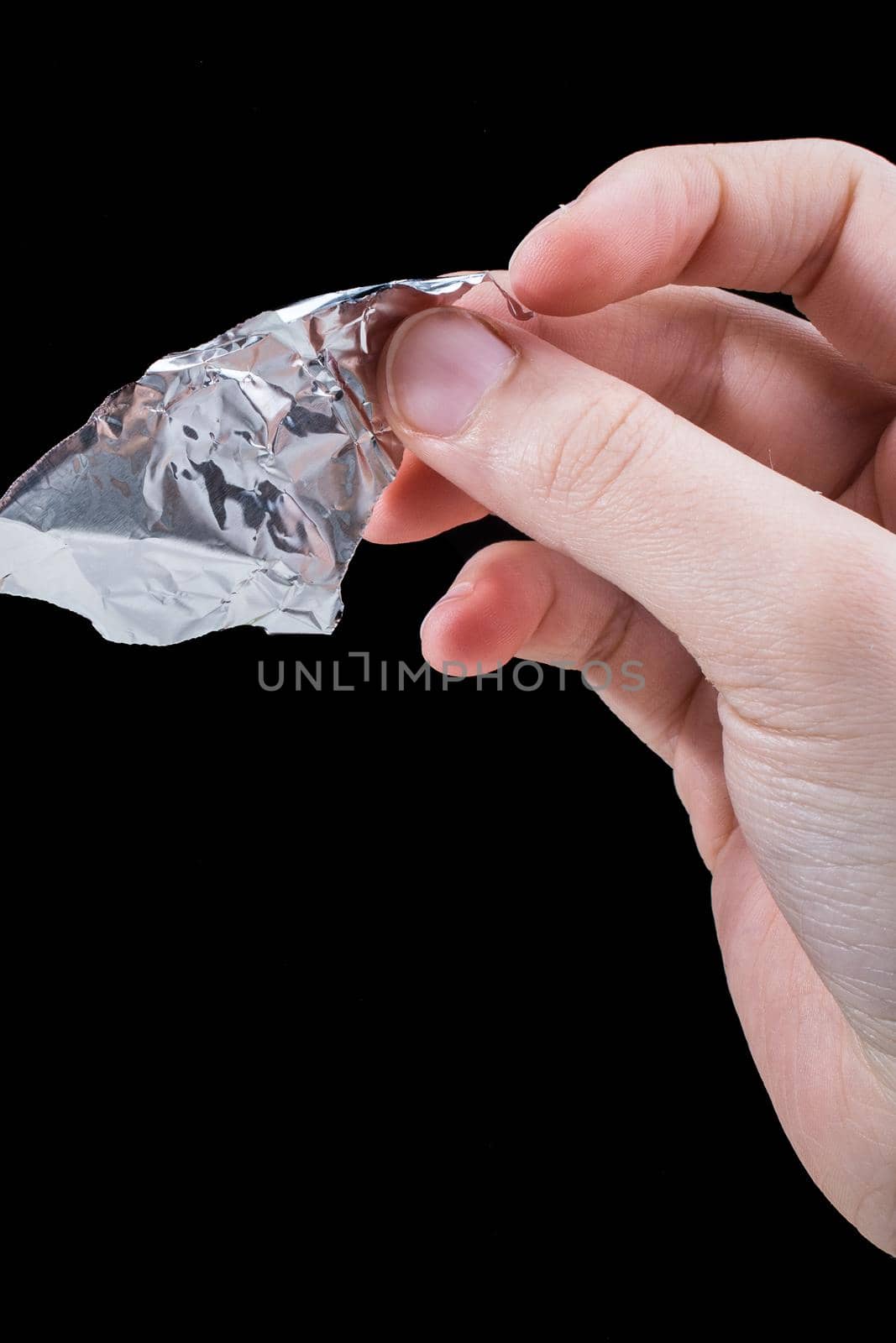 Hand tearing a heart shaped aluminium foil on a wooden background