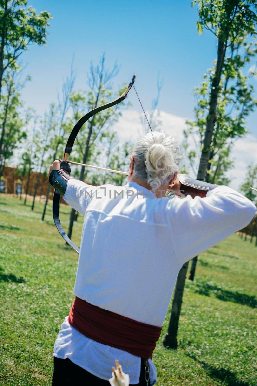 Archer in traditional clothes shooting an arrow by berkay