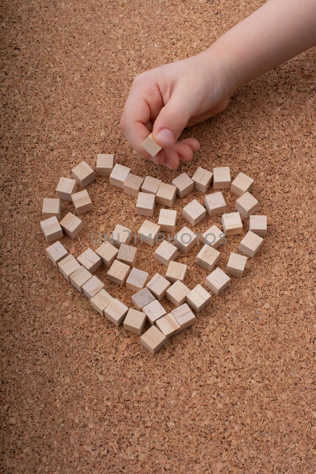 Little wooden cubes form heart shape or valentines day symbol and hand
