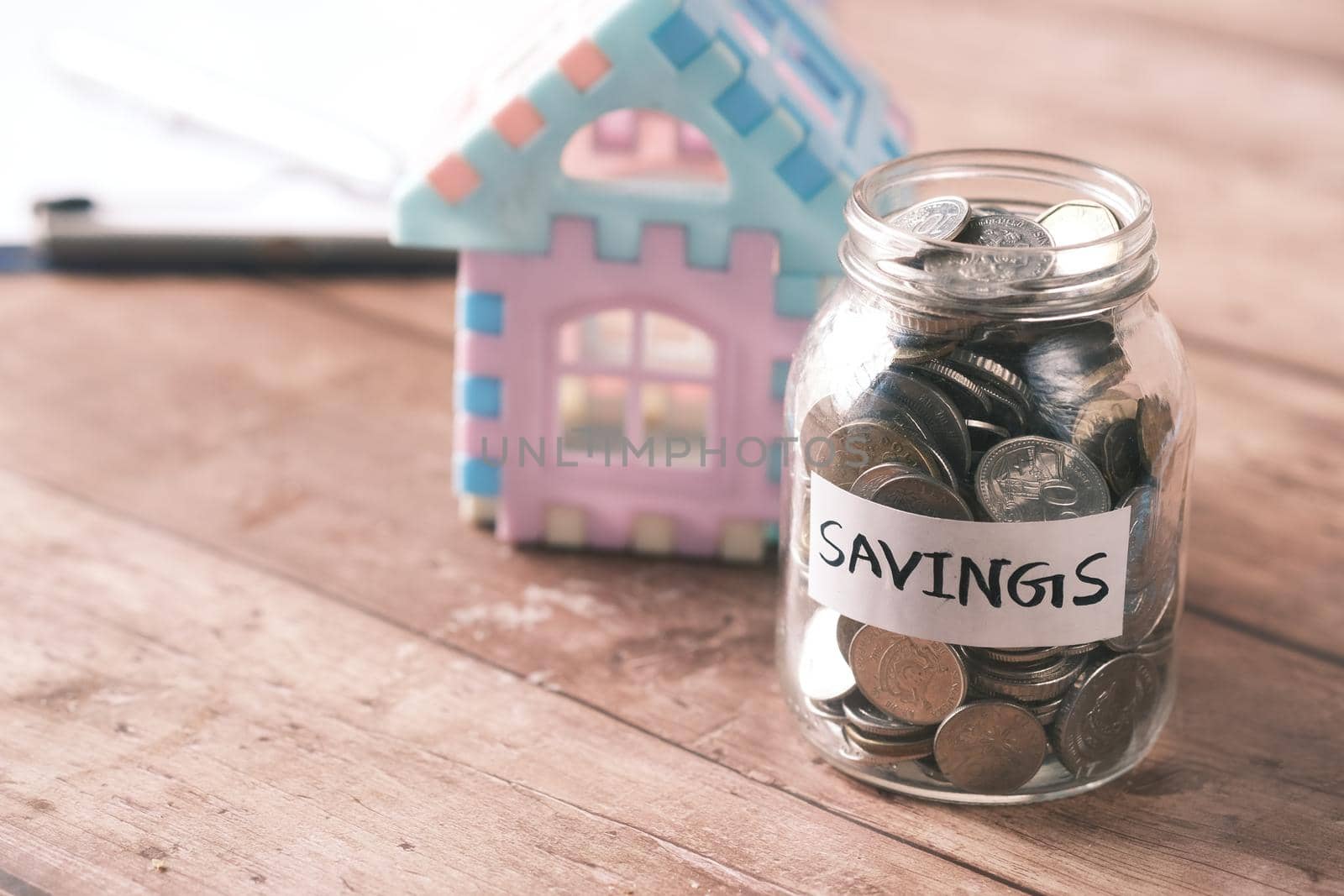 house finance concept with house model and saving coin jar on table .