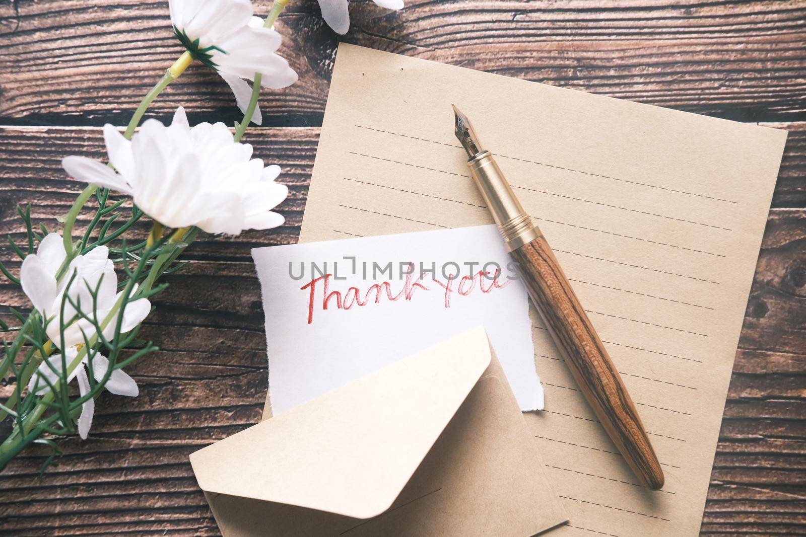 thank you message and envelope on wooden table.