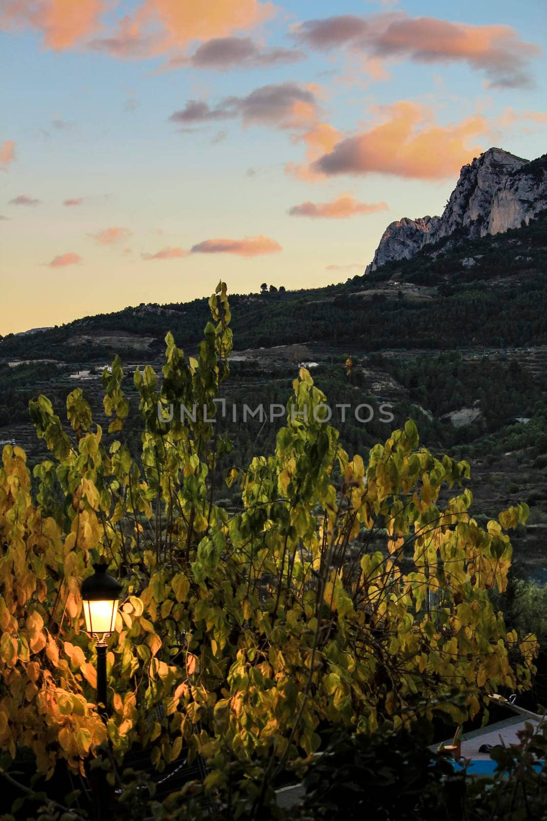 Sunset in Guadalest village with beautiful view of the valley. Vintage lamppost in the foreground.
