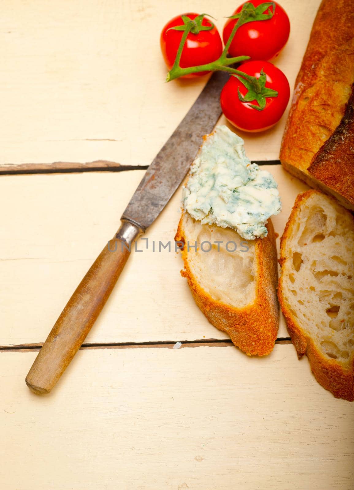 fresh blue cheese spread ove french baguette with cherry tomatoes on side