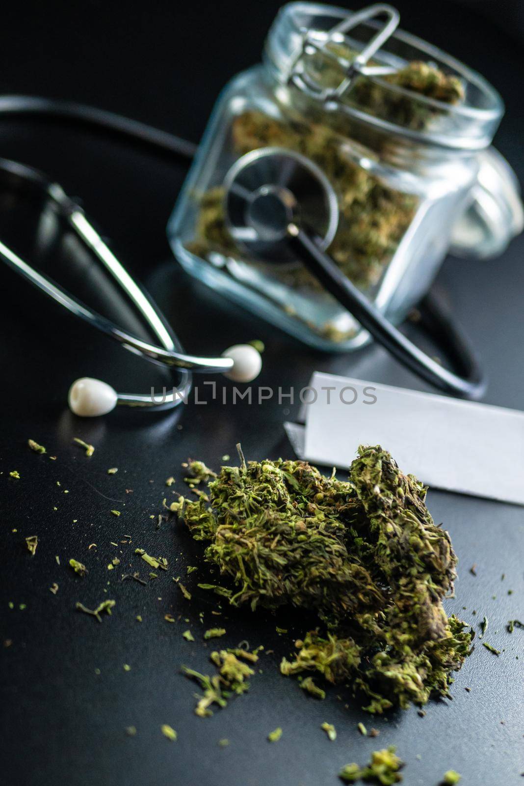 the Dry medical cannabis in a jar with a stethoscope on a black background