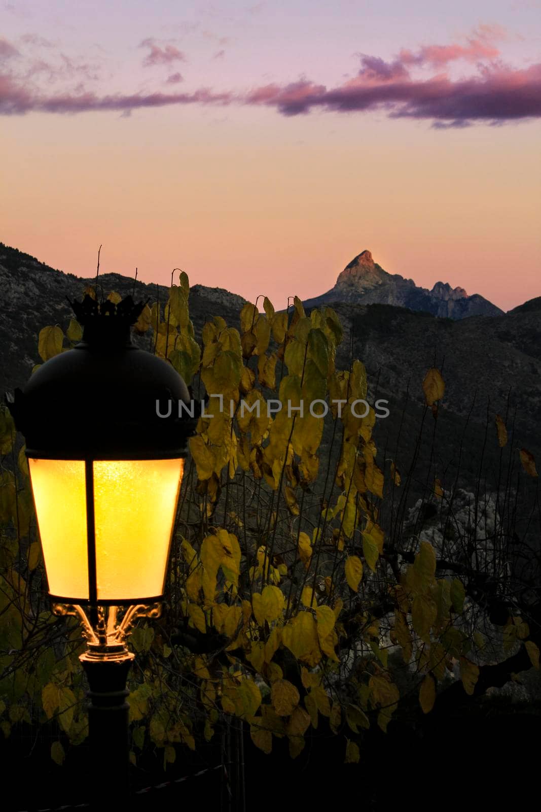 Sunset in Guadalest village with beautiful view of the valley. Vintage lamppost in the foreground.