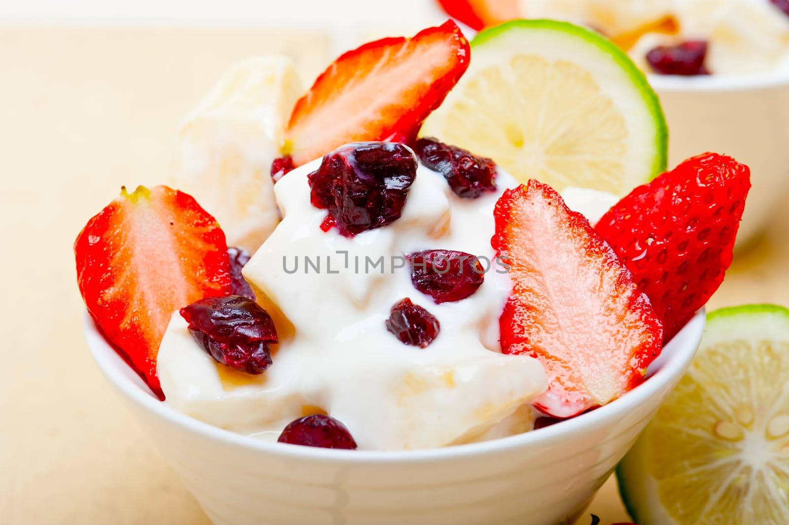 fruit and yogurt salad healthy breakfast over white wood table