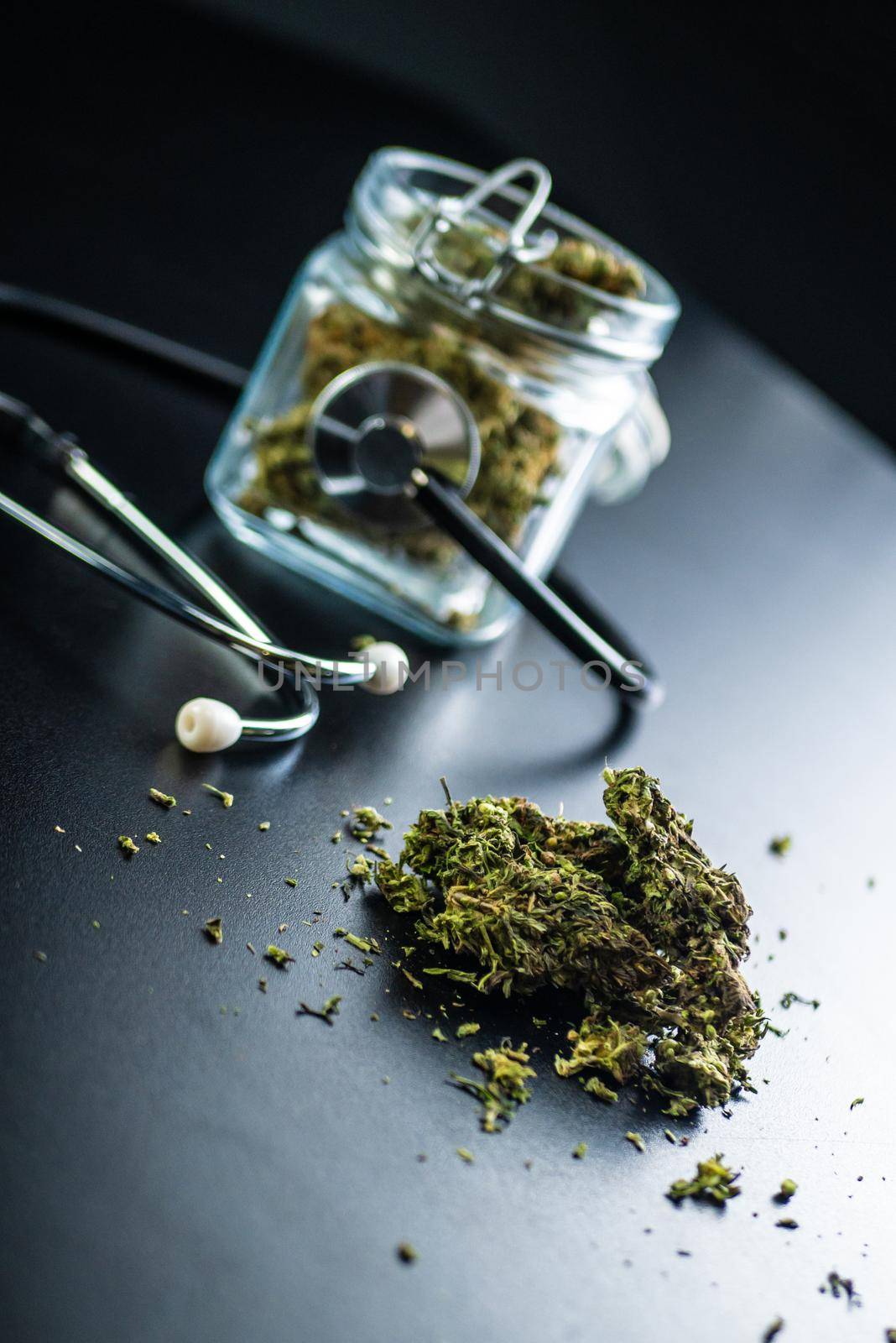 the Dry medical cannabis in a jar with a stethoscope on a black background