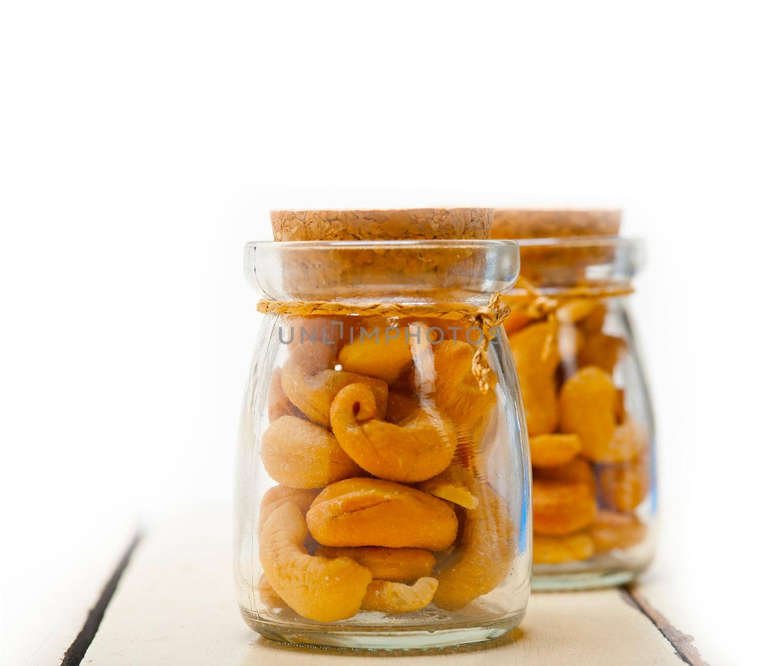 cashew nuts on a glass jar over white rustic wood table 