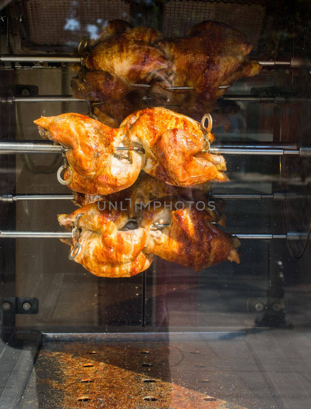 Chickens being grilled on metal spin in display by berkay