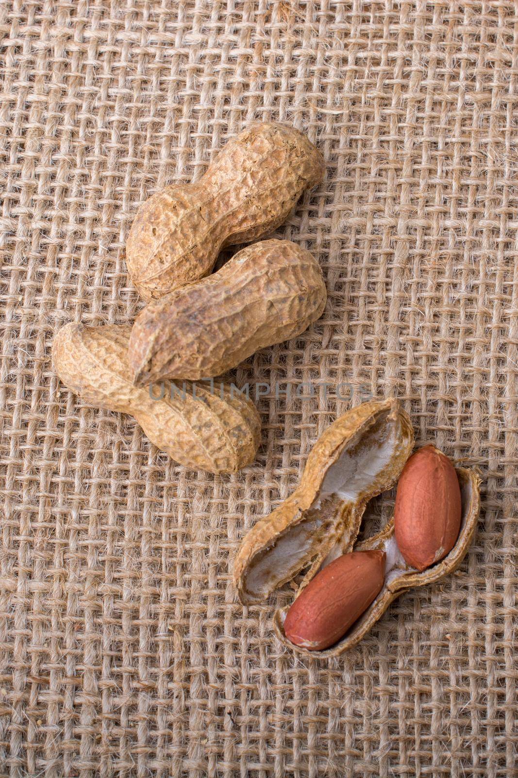Cracked open peanuts with shell on a linen canvas  by berkay