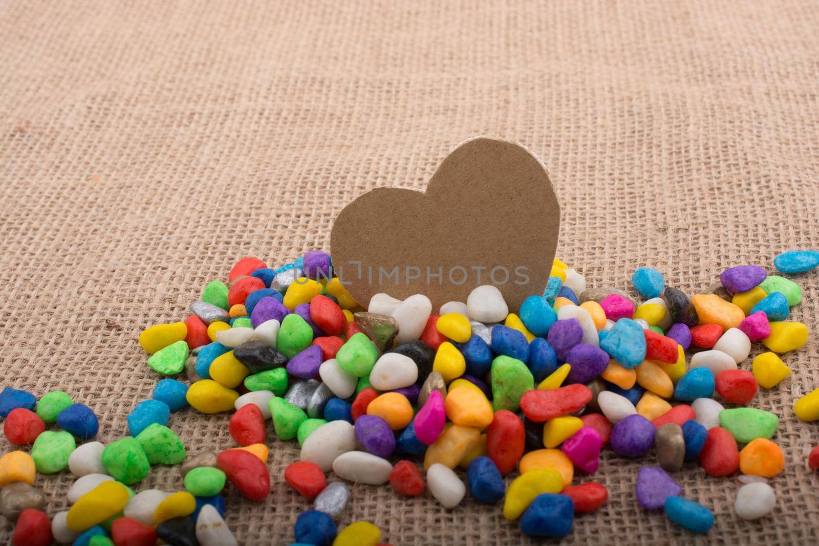 Paper heart amid pebbles on canvas ground by berkay