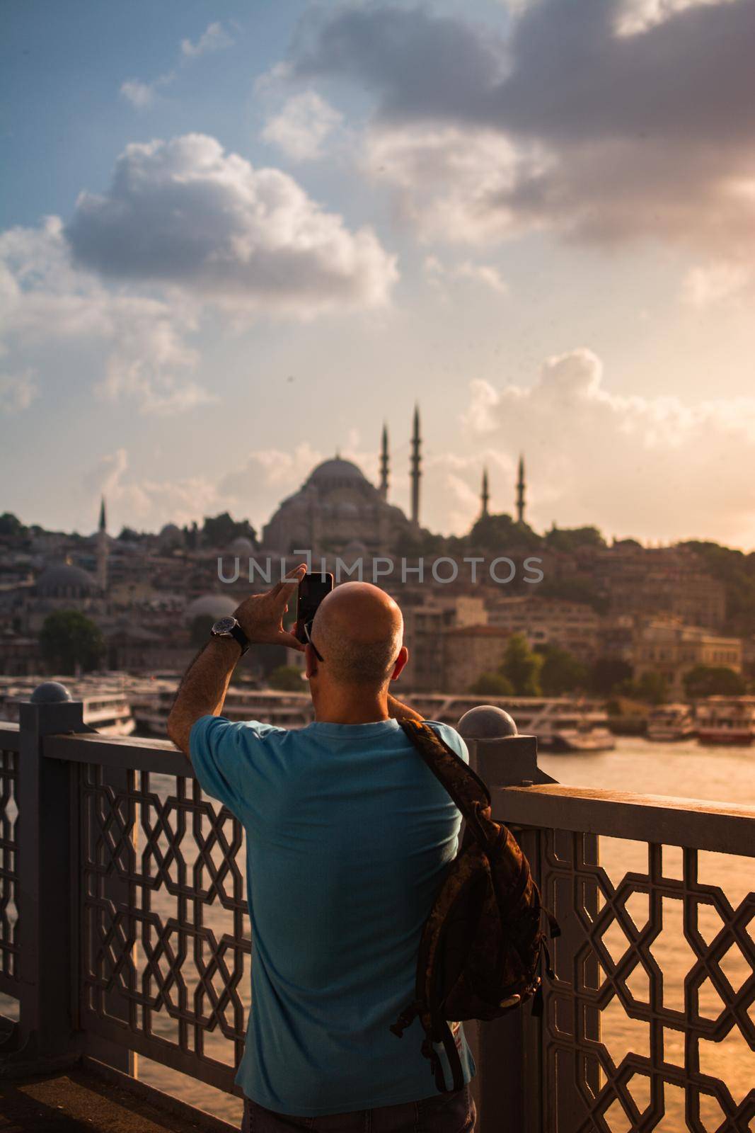 Man  taking pictures on Galata bridge. Vacation in Istanbul.  by berkay