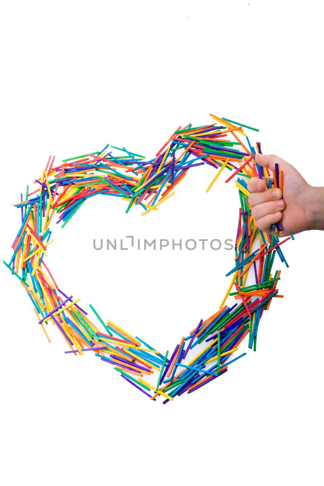 Coloured sticks formed heart shape by hand on white background
