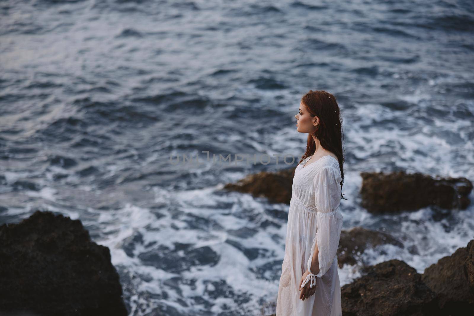 attractive woman in white dress posing by the ocean nature. High quality photo