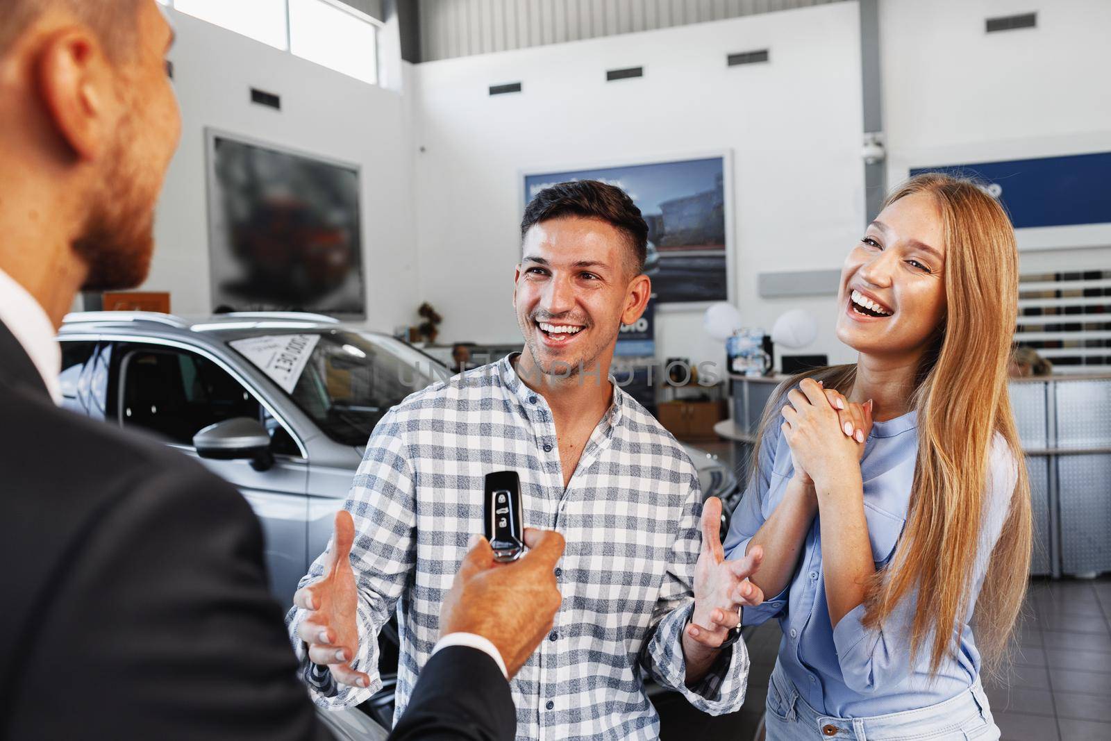 Cherrful young couple at the dealership buying a new car by Fabrikasimf