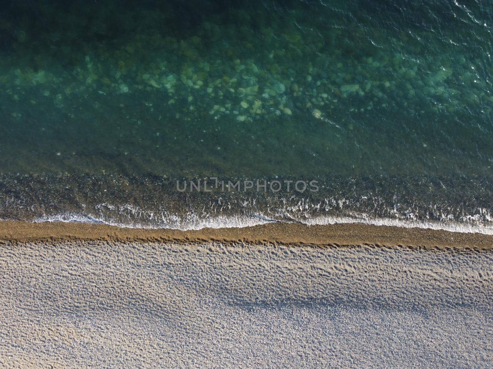 Aerial view from above on azure sea and pebbles beach. Small waves on cristal clear water surface in motion blur. Nature summer ocean sea beach background. Nobody. Holiday, vacation and travel concept by panophotograph