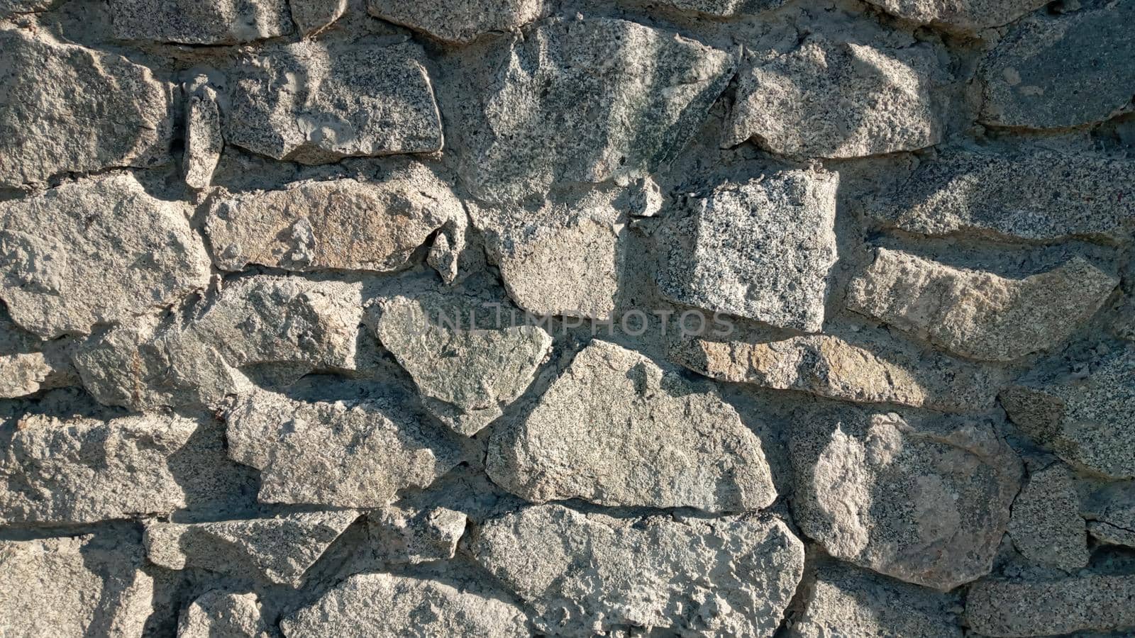 Stone wall texture background - grey stone siding with different sized stones. Part of a stone wall, for background or texture. Texture of a stone wall.